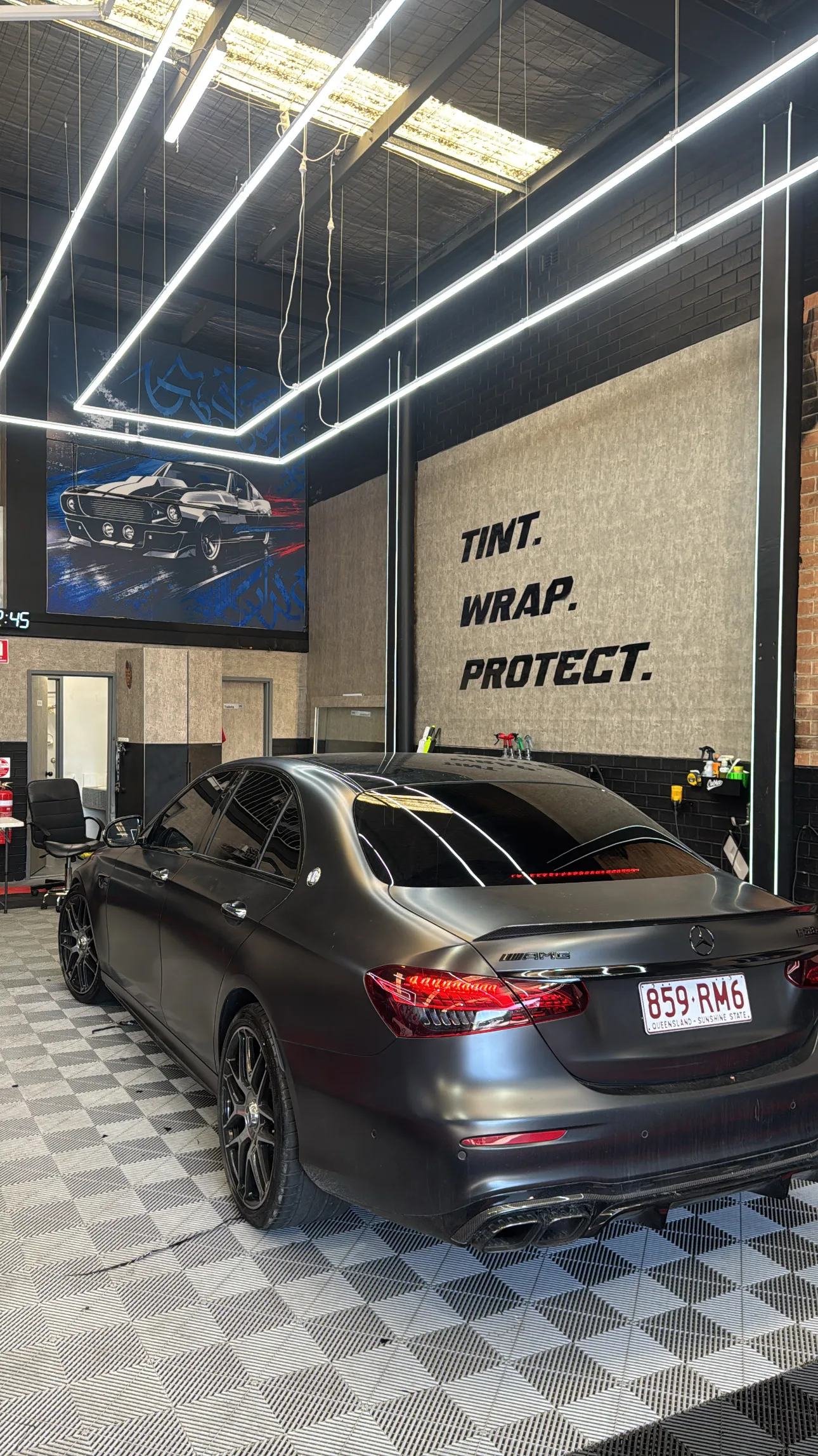 Dark Mercedes sedan inside Wally’s Tinting workshop